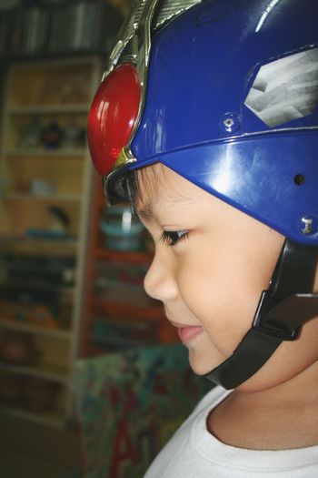 Side view of cute boy wearing helmet at home