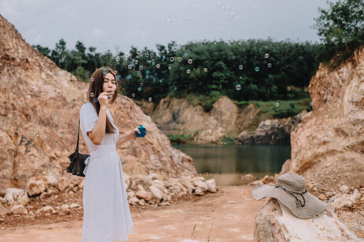 Young woman blowing bubbles against rocks