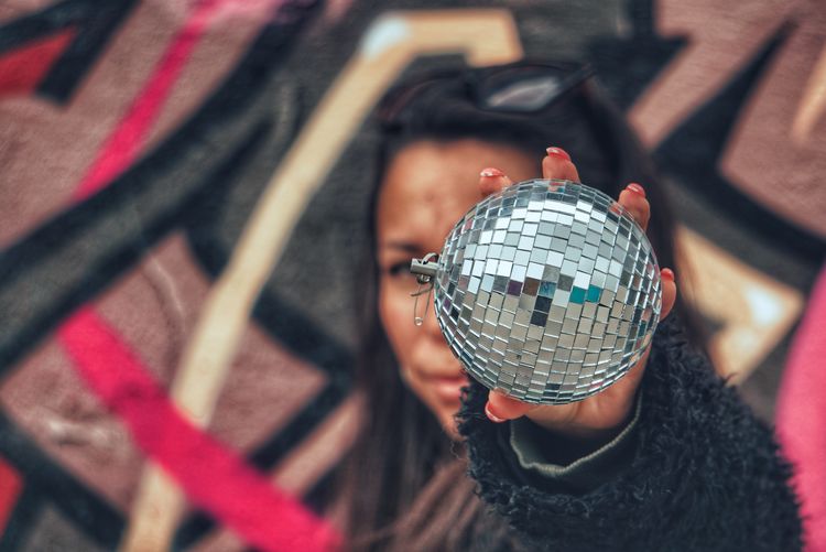 Portrait of woman holding disco ball against face