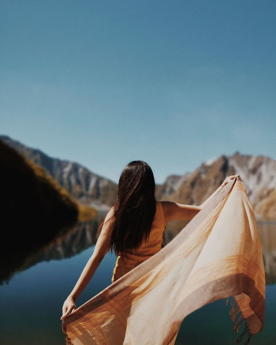 Rear view of woman with scarf standing against lake