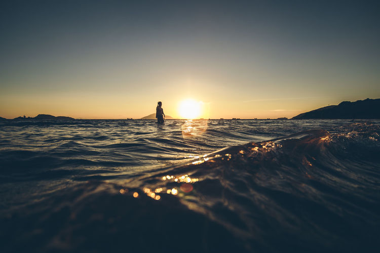 Scenic view of one person in sea at sunset