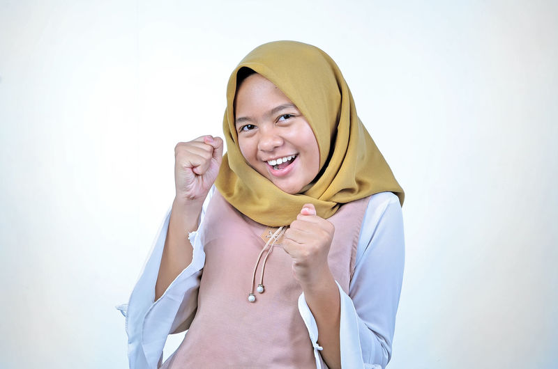 Asian woman wearing hijab happy and excited celebrating victory expressing big success, power, energy and positive emotions. celebrates for good job