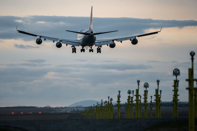 Low angle view of boeing 747 airplane flying against sky during sunset landing at budapest airport