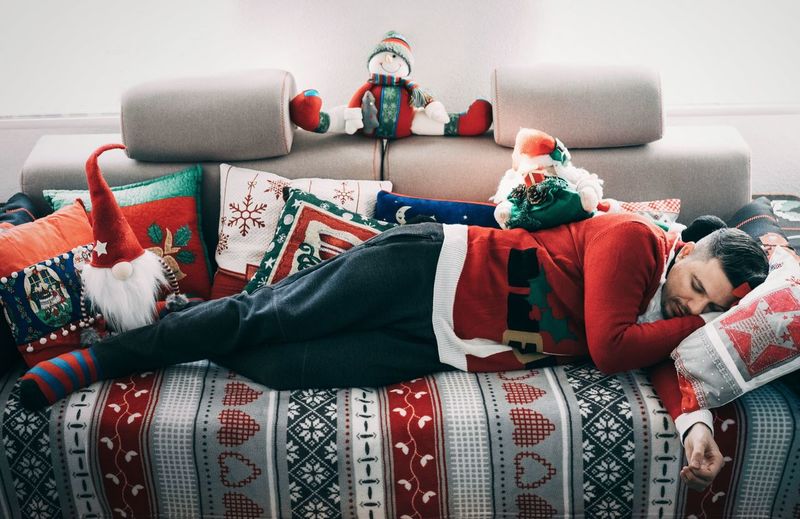 Mid adult man in santa costume sleeping on bed