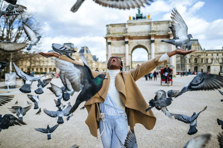 France, paris, happy young woman with flying pidgeons at arc de triomphe