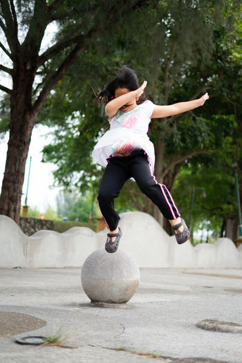 Outdoor portrait of a cute malaysian little girl with long hair jumping.