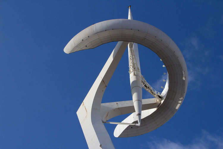 Low angle view and close up of communications tower against blue sky