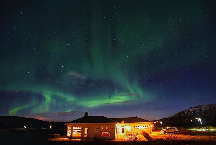 Idyllic view of aurora borealis over houses at night