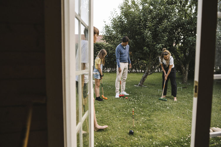 Parents playing polo with children in back yard