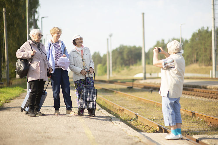 Senior women take a photo on a platform waiting for a train to travel during a covid-19 pandemic
