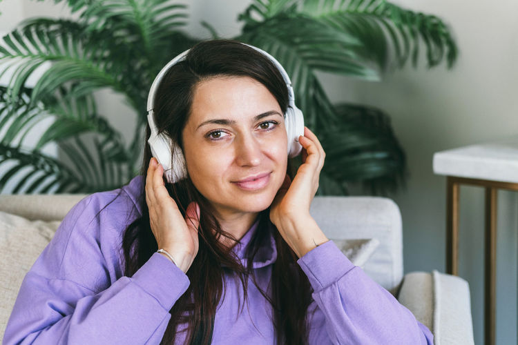 A woman in headphones listens to her favorite music at home on the couch.