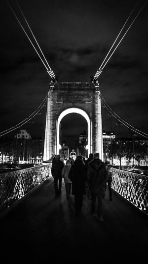 Rear view of people on suspension bridge at night