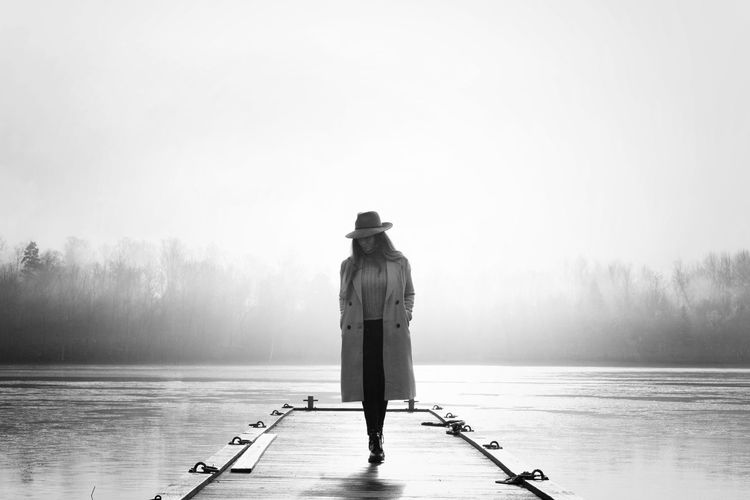 Rear view of man standing on pier over lake