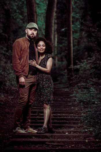 Full length of couple standing by tree in forest
