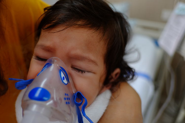 Close-up portrait of cute girl with oxygen mask at hospital