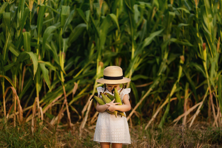 Portrait of cute girl holding corn standing outdoors