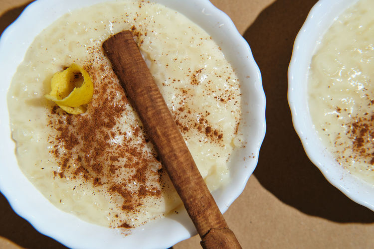 Foreground rice pudding decorated with lemon peel and cinnamon sticks