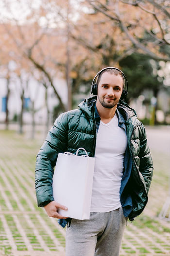 Portrait of mid adult man holding bag while standing outdoors