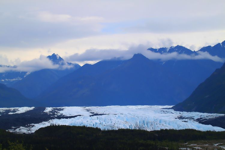 Scenic view of snowcapped mountains against a cloudy sky and receding glacier in alaska