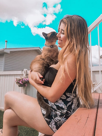 Midsection of woman with dog sitting outdoors