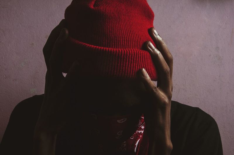 Close-up of silhouette man wearing red knit hat against wall