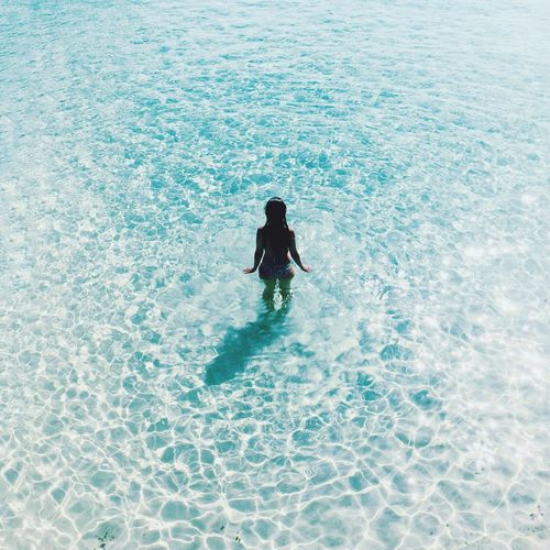 High angle view of young woman in sea on sunny day