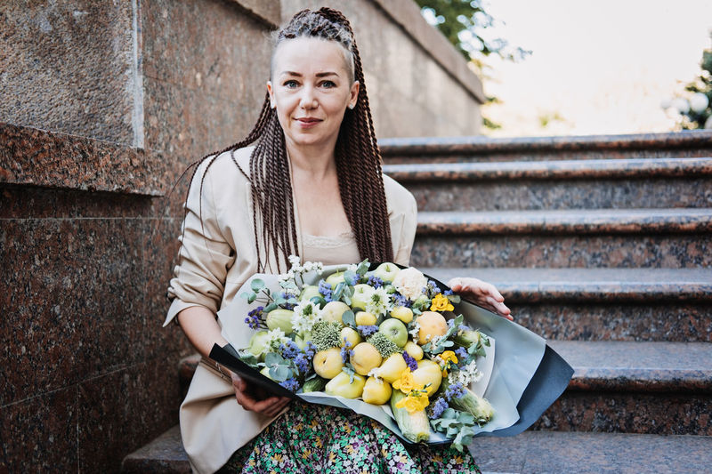 Flowers delivery. young modern hipster woman with dreadlocks receiving beautiful flowers bouquet