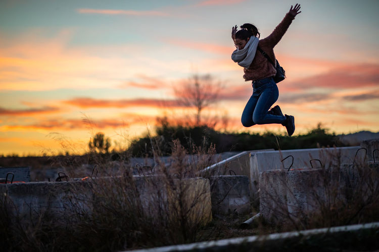Full length of woman jumping against sky during sunset