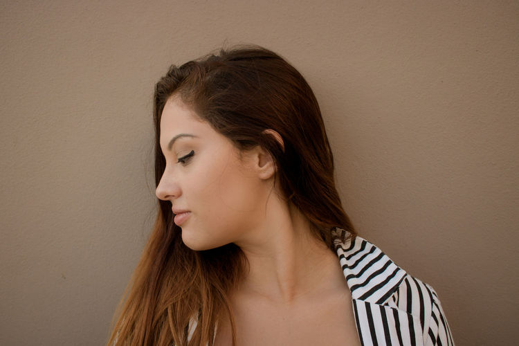 Young woman looking down against brown background