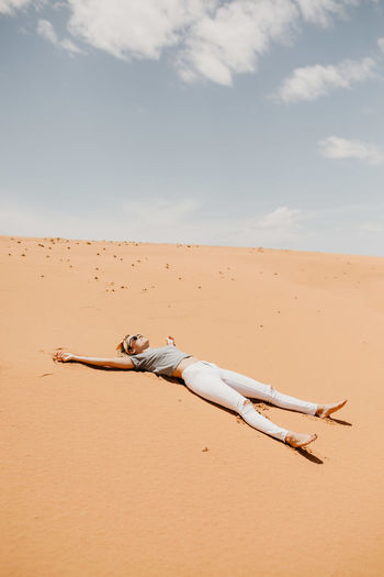 Woman lying down on desert in sunny day