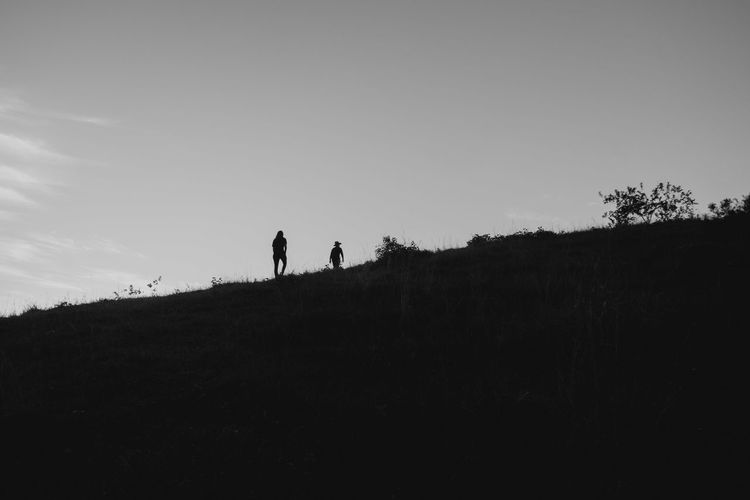 Silhouette people walking on field against sky