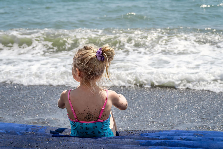 Girl child on the summer beach, view from behind