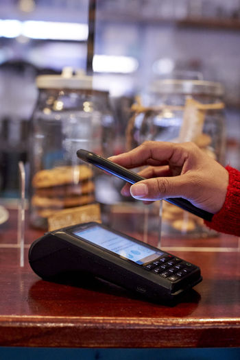Woman using mobile phone for making payment at cafe