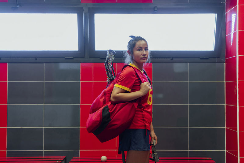 Lacrosse player standing with backpack in locker room