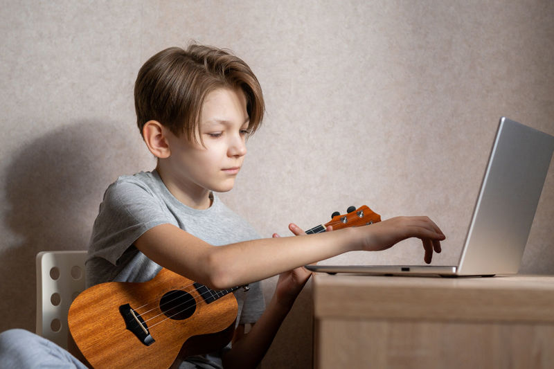 Boy playing guitar while sitting at home