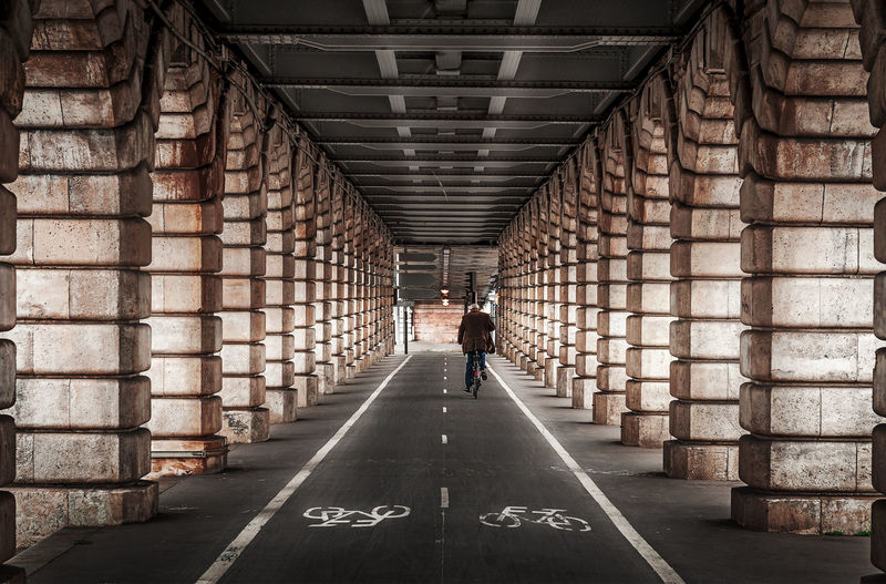 Rear view of man cycling in corridor