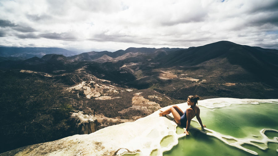 Panoram view with young girl sitting on the brink of mineral pool, mexico hierve el agua