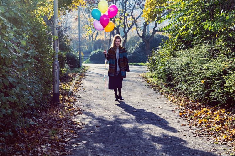 Full length of young woman walking with balloons at park