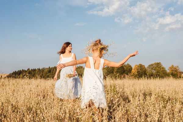 Mother and daughter by plants in land against sky