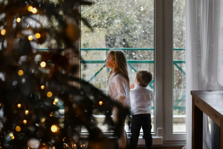 Children look at the snow through the window