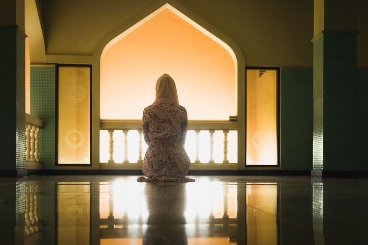Rear view of woman praying at mosque