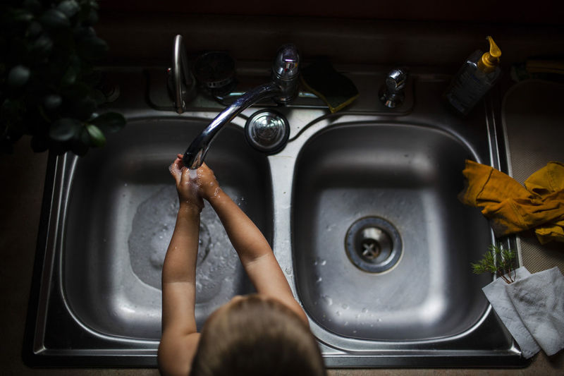 High angle view of boy washing hands in kitchen sink at home