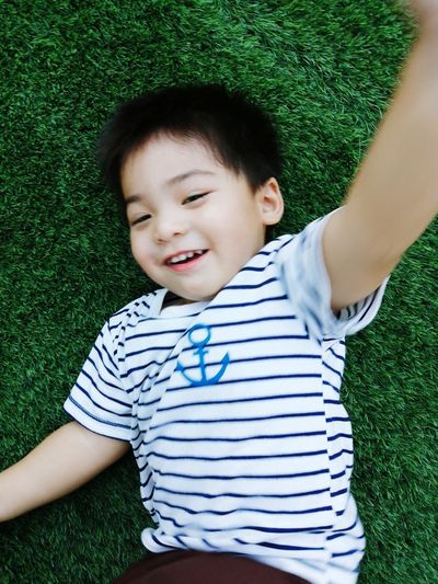 High angle view of cute boy lying on grass