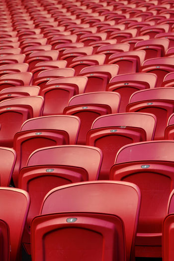 Empty red plastic seats in an empty stadium. many empty seats for spectators in the stands.