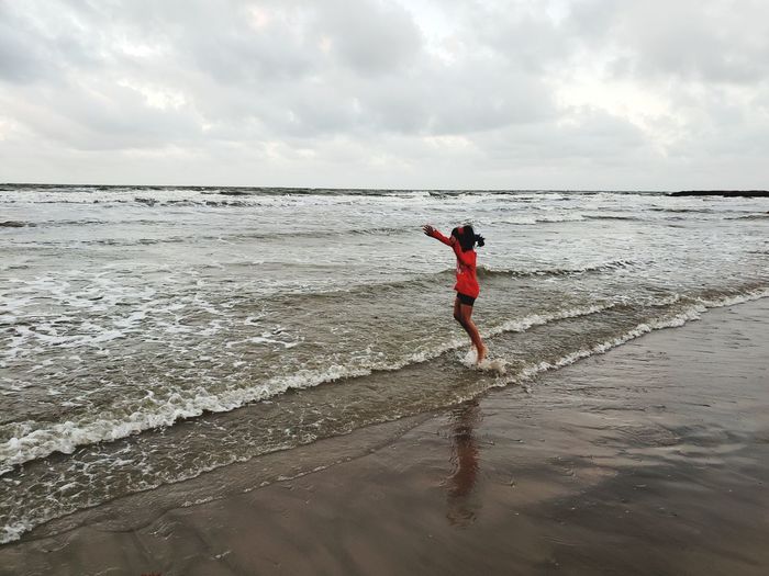 Full length of man standing on beach against sky
