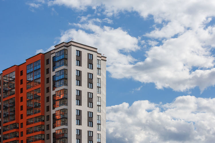 New high rise apartament building with  balcony and windows on blue sky with white clouds background