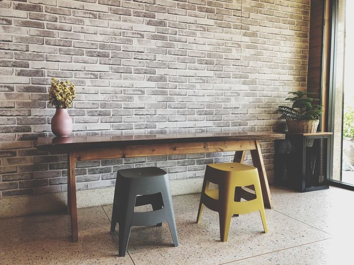 Empty chairs and table against brick wall