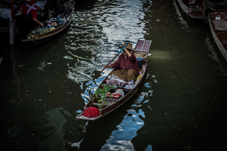 High angle view of woman on boat with vegetables in floating market