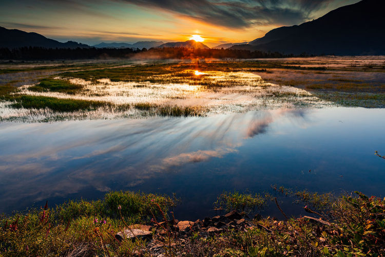 Spectacular sunrise over marshlands with mountain range in background, wonderful reflection