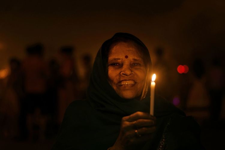 Close-up portrait of woman holding illuminated candle at night